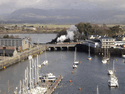 Taliesin (with the Vale of Ffestiniog at the rear) leaving Harbour Station and out across Britannia Bridge on the outward journey. (Photo: Alasdair Stewart)